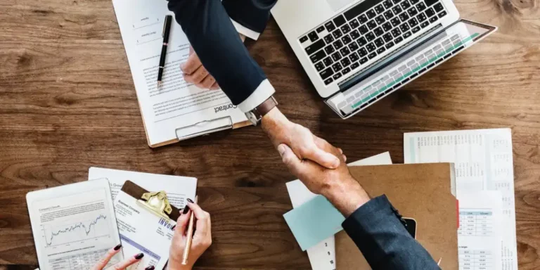 business men shaking hands over table