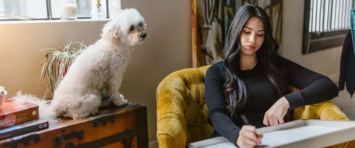 Woman working hard while her white dog sits beside her