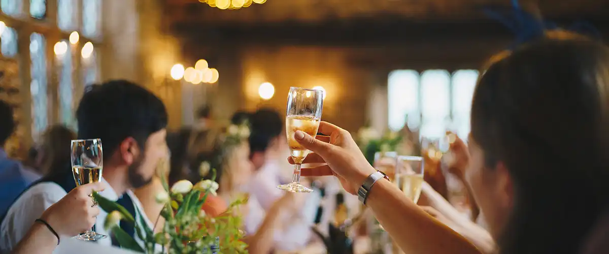 A woman holding up a glass for a toast at a wedding