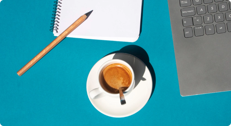 A pencil and paper sitting on table net to a cup of coffee and laptop