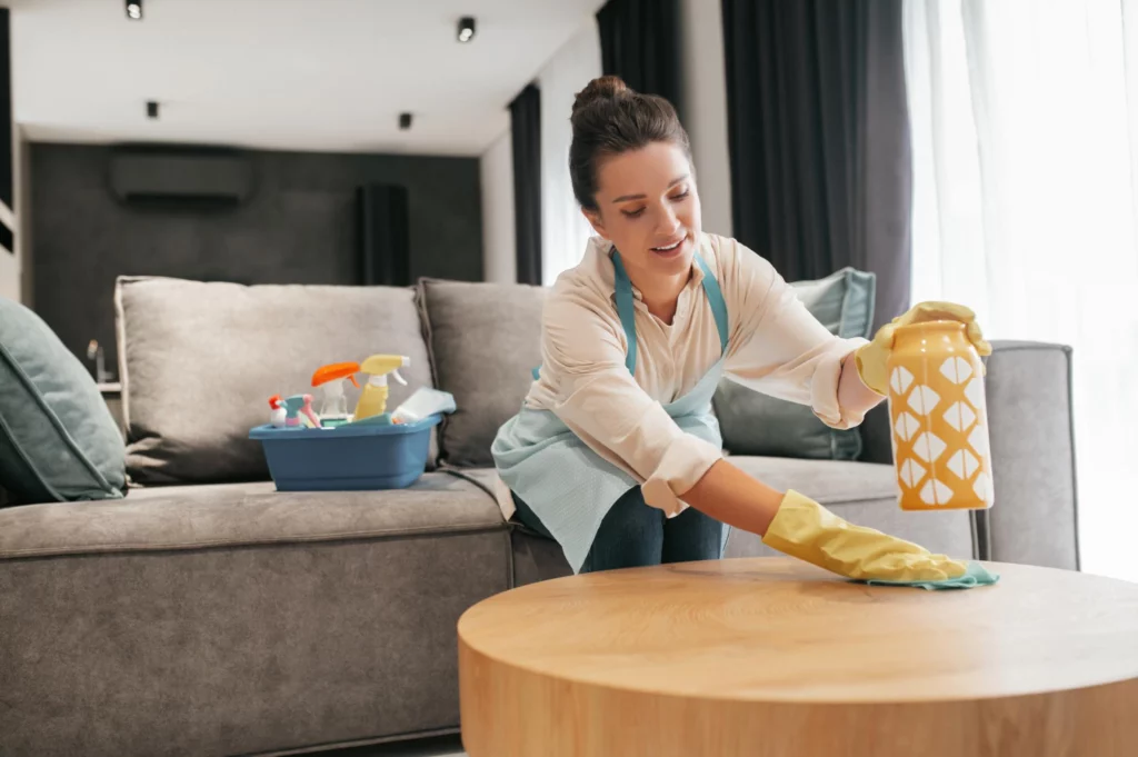 Woman wearing cleaning rubber gloves dusting furniture.