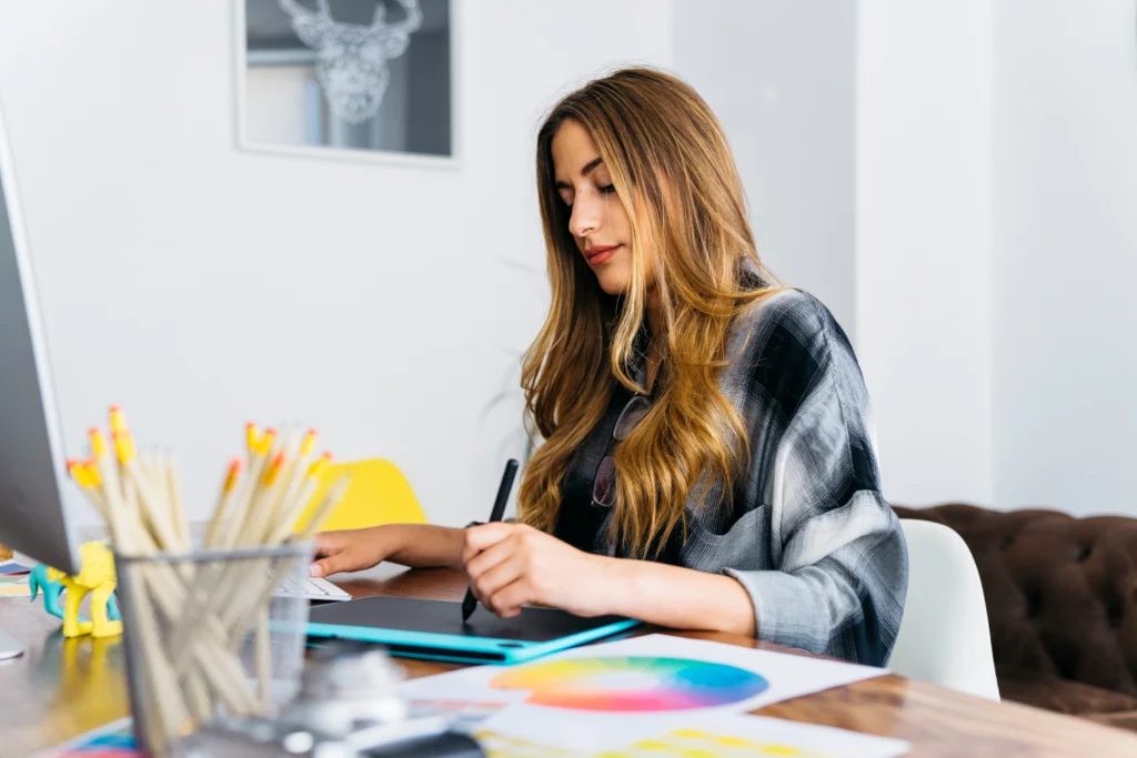 Woman creating digital art using her computer and Wacom drawing tablet.