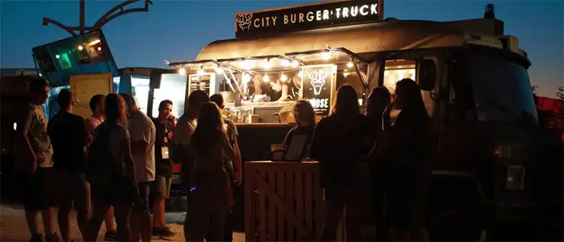 A crowd of people standing near food truck