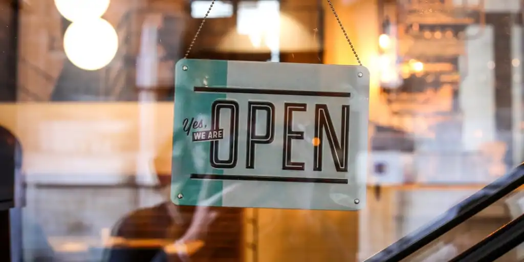 sign hanging inside glass window that says yes we are open