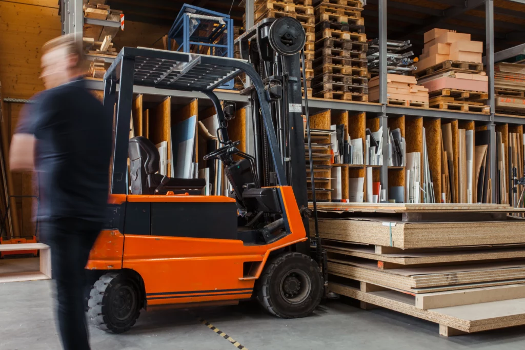 Stock image of warehouse with wood inventory and lift.