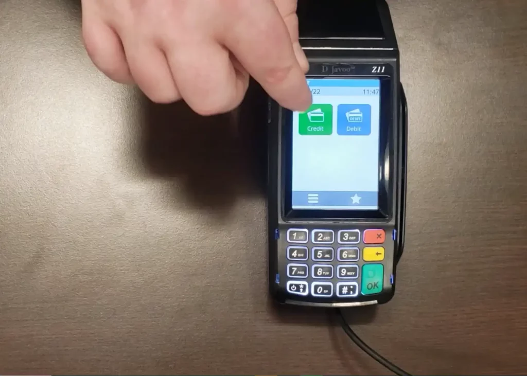 Man pointing at the credit card option on the Dejavoo Z11 credit card reader. There is also an option if a merchant’s customer wants to use a debit card.