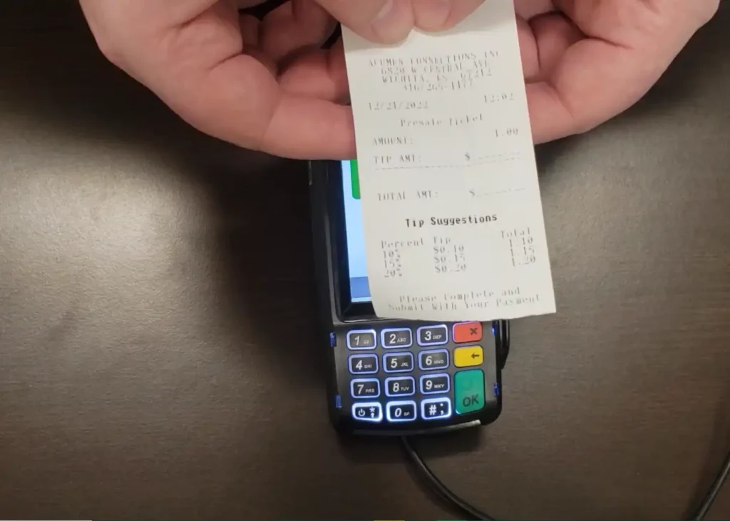 Man holding printed receipt above the Dejavoo Z11 credit card machine. At the bottom of the receipt, it says “tip suggestions” and has tip prompts for the customer to choose between.