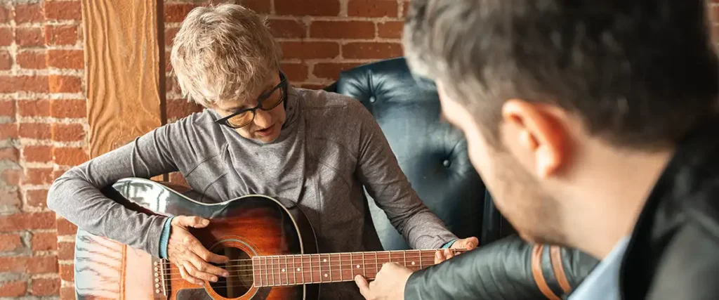 Woman learning how to play guitar during lessons