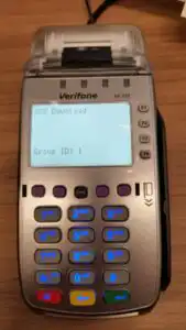 Verifone terminal on table displaying VCS Download Group ID